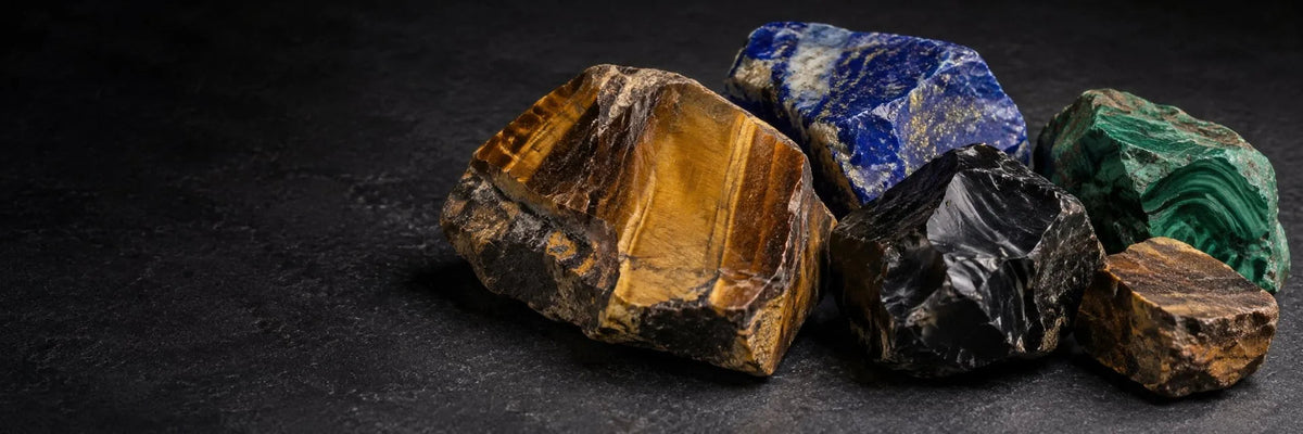 Raw tiger eye, lapis lazuli, malachite and black obsidian on dark stone